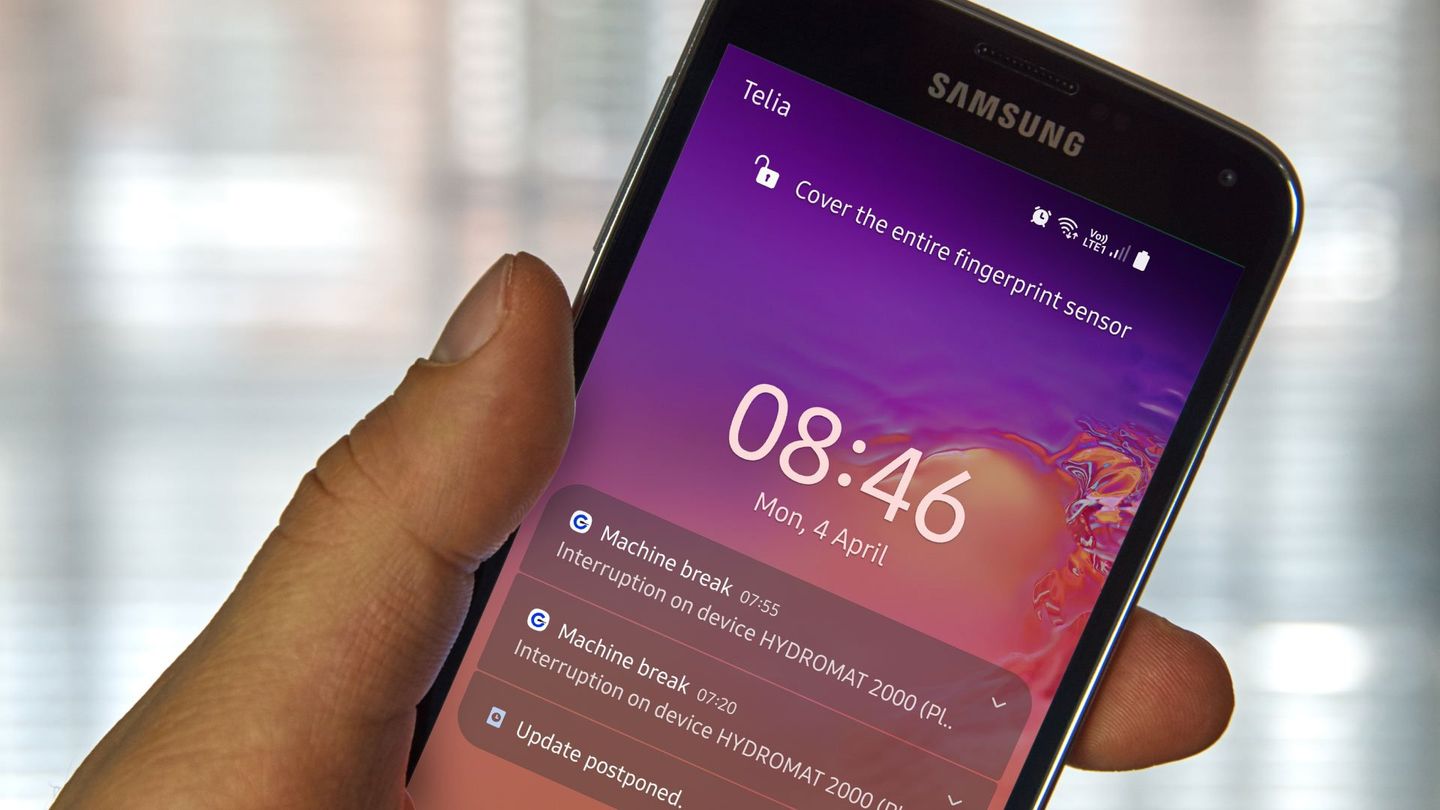 Zbliżenie ekranu smartfona Samsung wyświetlającego powiadomienia, w tym przerwy w działaniu urządzenia i odroczenie aktualizacji, z rozmytym tłem okna.