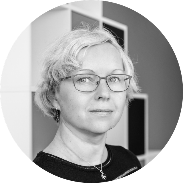 Czarno-biały portret osoby z krótkimi włosami w okularach i patrzącej w kamerę.